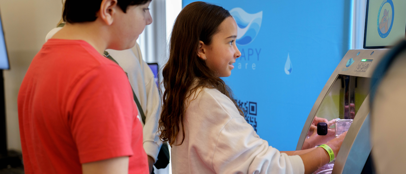 A guest washes their hands via the Soapy device