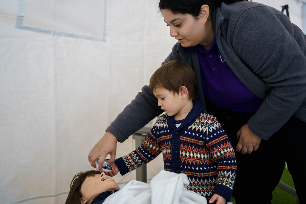 An LSC staff member helps a young guest try out the TytoCare
