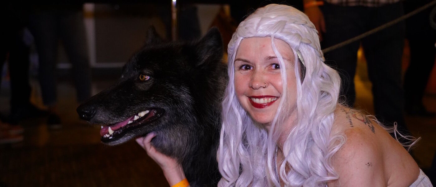 Girl dressed as Daenerys Targaryen pets a wolfdog