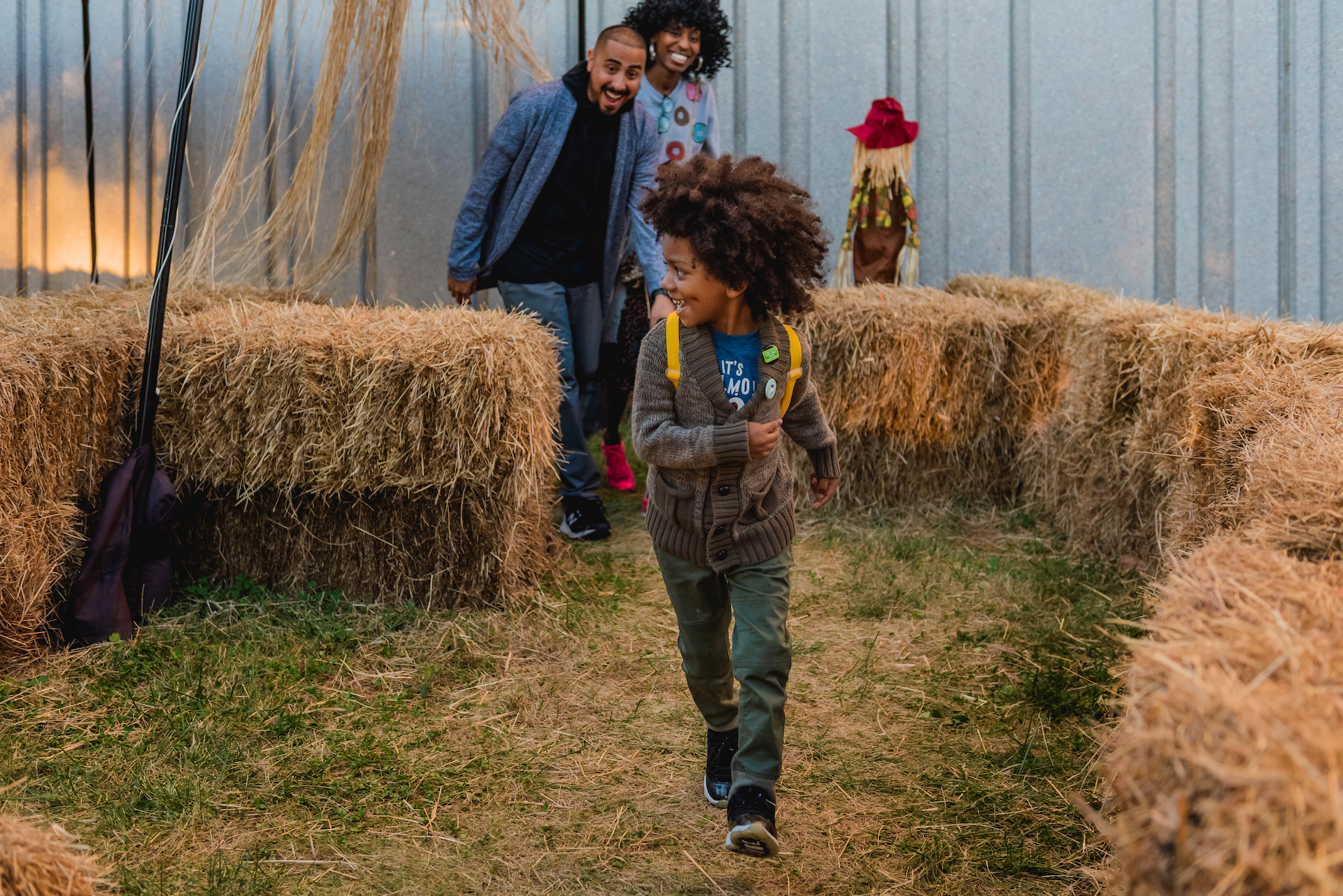 Family running through scarecrow hay maze