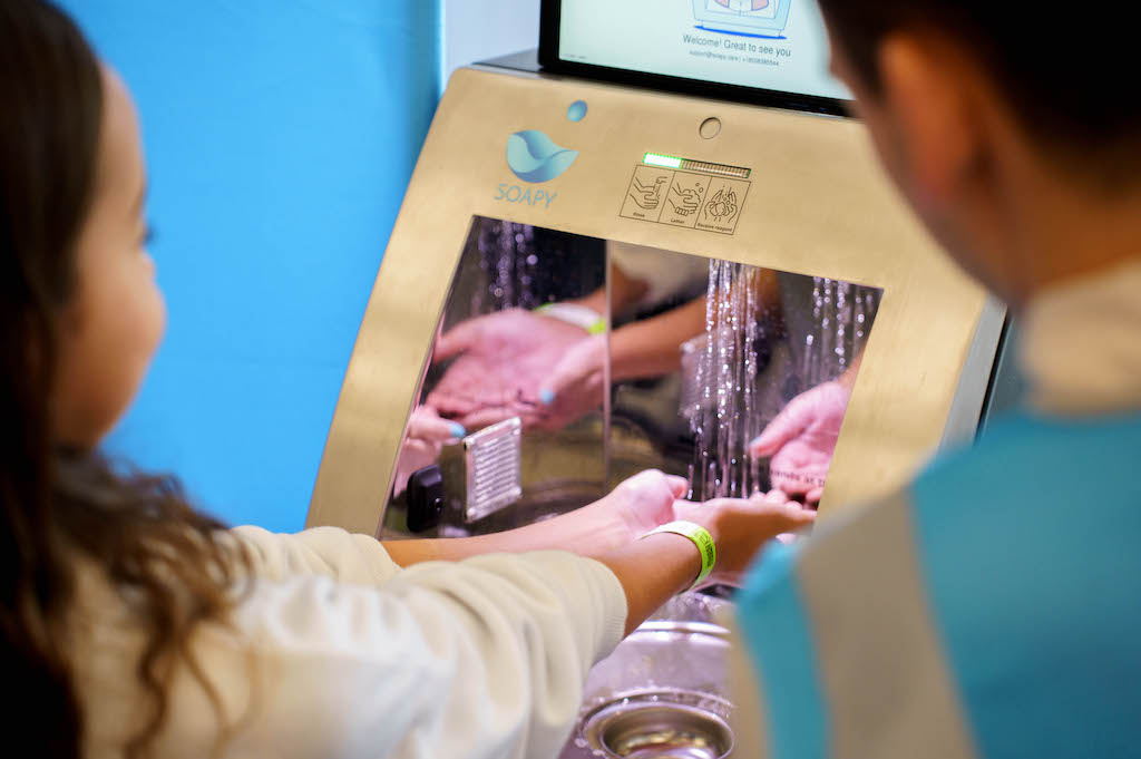 A guest washes their hands via the Soapy device