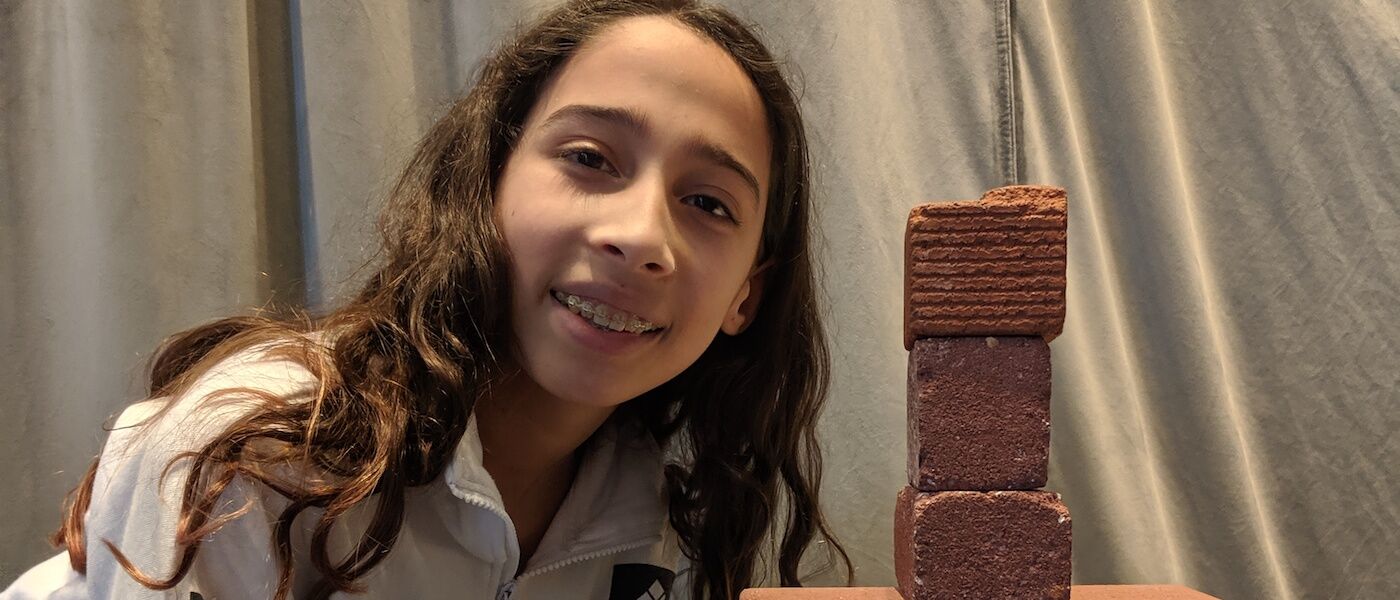 Girl shows off bricks held up by paper