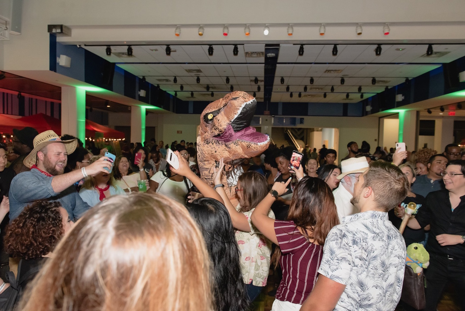 Guests party on the crowded dance floor with a dinosaur costume character
